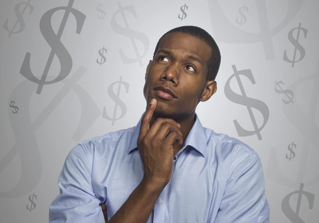 Man in a blue shirt looking up thoughtfully against a background of dollar signs while weighing truck financing costs