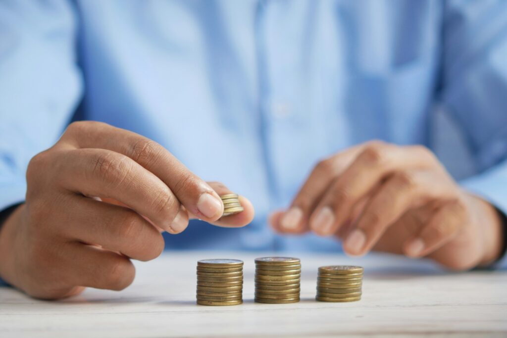 Man stacking piles of coins, representing costs