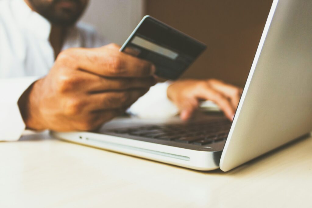 Person holding a credit card while typing on a laptop, applying for semi truck financing online