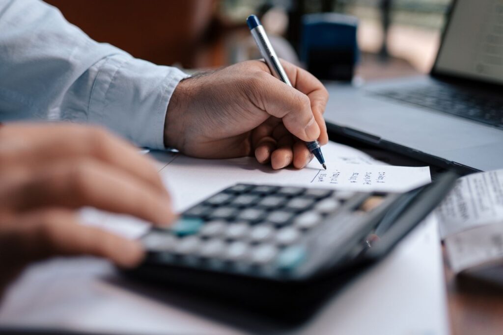 Person using a calculator and writing figures on paper to estimate semi-truck loan payments
